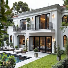 a large white house with lots of windows and balconies next to a pool