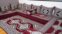 a couch covered in red and white rugs on top of a wooden floor