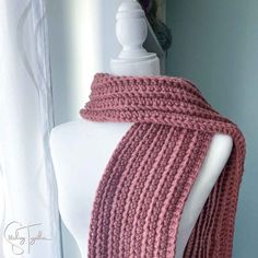 a close up of a mannequin wearing a pink knitted scarf on a dummy