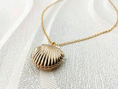 "A gorgeous and beautiful gold seashell locket necklace. It features a shining gold seashell and suspends in a gold finished brass chain along with lobster claw clasp closure. The shell locket inside can hold pictures in both side 16mm x 14mm. The necklace is available in seashell locket necklace only, or adding a stimulated cream white pearl charm along with the seashell locket necklace. The pearl is genuine Swarovski 6mm pearl. It is a wonderful idea for gift giving or as a little treat for yo Yellow Gold Shell-shaped Necklace Gift, Gold Shell Necklace With Ocean-inspired Style, Gold Shell Necklace Ocean-inspired, Gold Shell Ocean-inspired Necklace, Yellow Gold Shell Necklace For Gift, Gold Shell Necklace Perfect As A Gift, Gold Ocean-inspired Shell Necklace, Ocean-inspired Gold Shell Charm Necklaces, Gold Ocean-inspired Charm Necklace For Gift