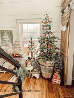 a small christmas tree in a room with wooden floors and white walls, surrounded by other holiday decorations