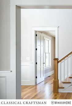 an empty room with white walls and wood floors, stairs leading to the second floor