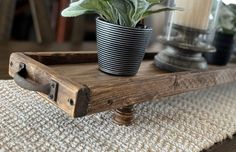 a potted plant sitting on top of a wooden tray next to a candle holder