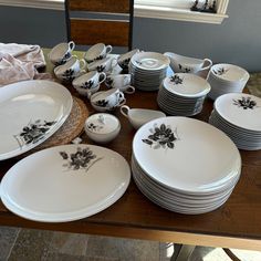 a table topped with lots of white plates and bowls filled with black flowers on them