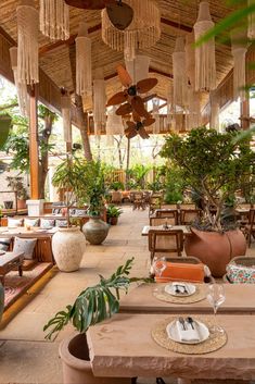 an outdoor dining area with tables, chairs and potted plants on the table top