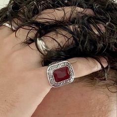 a close up of a person wearing a ring with a red stone in the middle