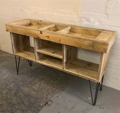 a wooden table with two open compartments and hairpin legs in front of a white brick wall