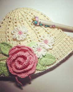 a crocheted hat with flowers on it and a toothbrush next to it