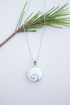 "Handmade Sterling Silver Necklace with a round polished natural shiva shell and a silver chain. This unique piece is formed by a Shiva shell of 18mm diameter into a silver pendant. Shiva eye is also called \"Santa Lucia Stone\" or \"Ojo de Santa Lucia\" in some areas. A completly natural and beautiful shell. You can wear it on both faces of the shell. This shell is the a perfect present for all those women who loves the sea and natural beauty. Details: - 925 Sterling Silver stamped. - Able for White Sterling Silver Shell Necklace For Gift, White Sterling Silver Shell Necklace As Gift, Silver Round Shell Necklace For Gifts, Silver Mother Of Pearl Round Shell Necklace, Silver Round Mother Of Pearl Shell Necklace, Silver Mother Of Pearl Shell Necklace, Silver Shell Necklace With Round Pendant For Gift, Shiva Eye, Spiral Necklace