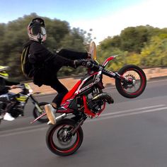 a person on a motorbike doing a trick in the air with another motorcycle behind him