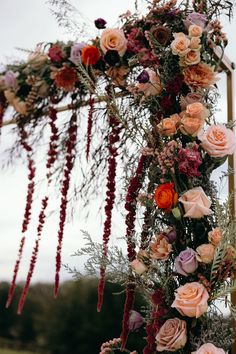 an arrangement of flowers and greenery is arranged on the side of a wooden structure