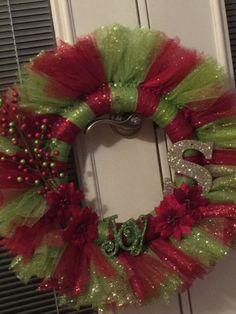 a red and green christmas wreath with the letter e on it's front door