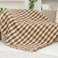 a brown and white blanket sitting on top of a couch