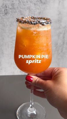 a hand holding a glass with a pumpkin pie spritz in it and the words pumpkin pie sprinkled on top