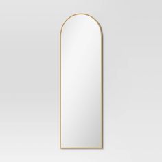 an arch shaped mirror with gold trim on the front and bottom, against a white background