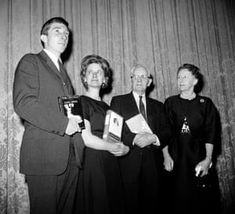 an old black and white photo of three people holding awards in front of a curtain