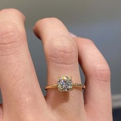 a woman's hand with a diamond ring on top of her finger, showing the center stone