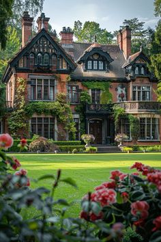 a large house with many windows and lots of flowers in the front yard, surrounded by greenery