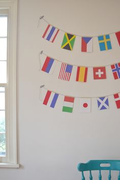 an olympic flag garland hanging from a chair in front of a wall with flags on it