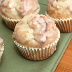 several muffins sitting on top of a green cloth covered in white icing