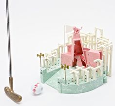 a miniature golf course with a pink and white statue next to it on a white surface