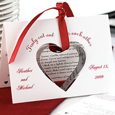 two heart shaped cards with red ribbon tied to them on top of some silver plates