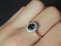 a woman's hand holding an engagement ring with a blue stone in the center