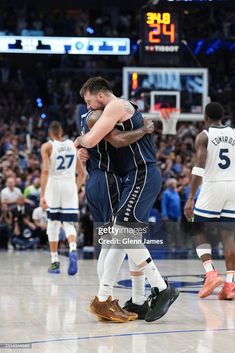 two basketball players hugging each other in the middle of a court with fans watching them