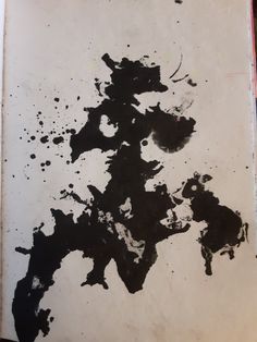 a piece of paper with black ink splattered on it, sitting on top of a table