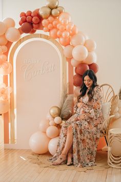 a pregnant woman sitting on a chair in front of balloons and a sign that says baby corbbett