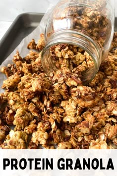 a glass jar filled with granola sitting on top of a pan full of granola