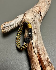 a yellow and black beaded bracelet sitting on top of a piece of driftwood