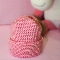 a pink knitted hat sitting on top of a table next to a stuffed animal