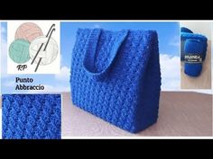 a crocheted blue bag sitting on top of a table next to a ball of yarn