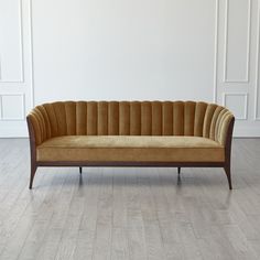 a couch sitting on top of a hard wood floor next to a white wall in an empty room