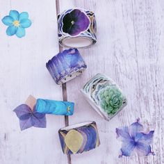 four different types of paper flowers on a white wooden surface