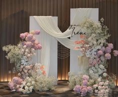 two white and pink flowers are on the floor next to an archway with drapes