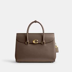 Our Broome has all the effortless cool of its namesake Soho street. The spacious foldover silhouette is crafted of luxe refined leather with a high shine finish and secures with our pushlock “C” closure. Featuring pockets inside and out for easy organization and room for a 16” laptop carry it by hand or use the detachable strap to wear it crossbody. | Coach Broome Carryall Bag 36 - Women's - Brass/dark Stone Coach Work Bags For Women, Luxury Handbags Coach, Latest Coach Handbags, Coach Bags 2021, Coach Bags Handbags Coach, Coach Tatum Carryall 40, Coach Purse Coach, Studio Shoulder Bag Coach, Coach Dreamer Bag