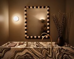 a bathroom sink with a mirror and lights on the wall above it, along with decorative items