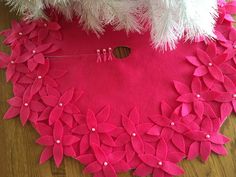 a pink and white christmas tree skirt on a wooden floor