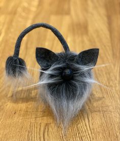 an animal made out of felt sitting on top of a wooden table next to a pair of headphones