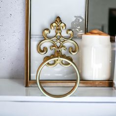 a gold towel ring sitting on top of a white counter next to a candle holder