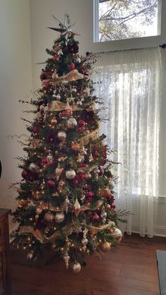 a decorated christmas tree in front of a window