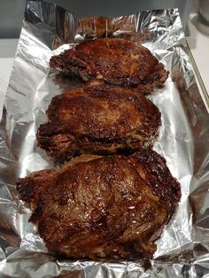 three steaks sitting on top of aluminum foil