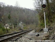 an old railroad track in the middle of a wooded area with trees on both sides