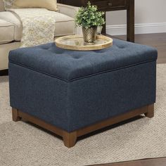 a blue ottoman with a tray on it in front of a couch and coffee table