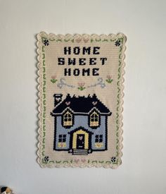 a cross - stitch house hanging on the wall next to a teddy bear and stuffed animal