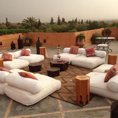 an outdoor seating area with white couches and pillows