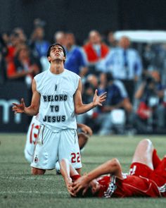 a man standing on top of a soccer field next to another person laying on the ground