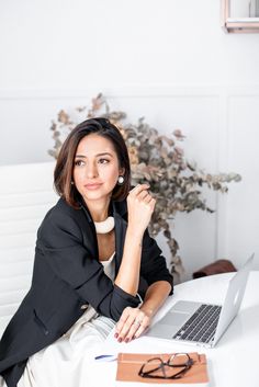 a woman sitting at a table with a laptop computer in front of her and looking up